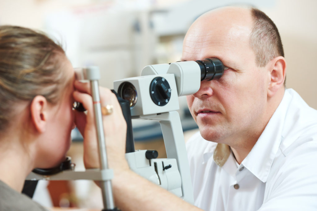 Optometry concept. Male optometrist optician doctor examines eyesight of female patient in eye ophthalmological clinic